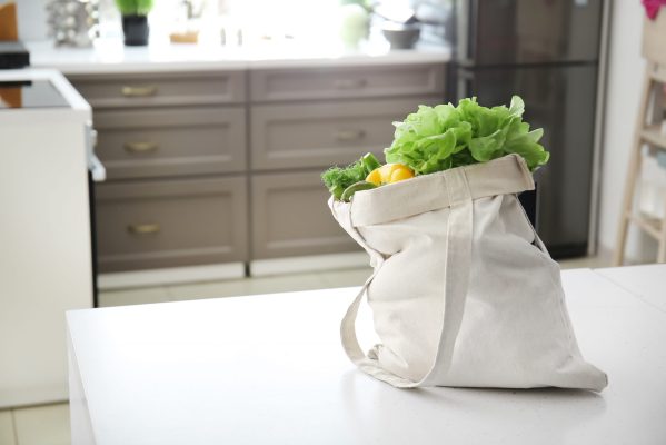 Eco bag with fresh vegetables on table in kitchen