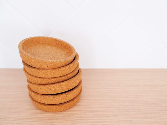 Brown wooden coasters stacked on kitchen table.
