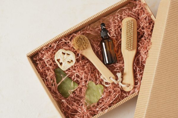 a set of cosmetics and body care products in a box with paper filler, massage oil, gua sha scrapers and a brush, gift or delivery, natural cosmetics concept, CO2 neutral