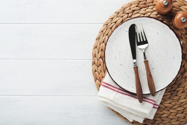 Vintage zero waste silverware. Rustic vintage set of white plate, wooden spoon and fork on napkin for dishes from water hyacinth on light gray concrete background. Empty dishes. Top view. Mock up.