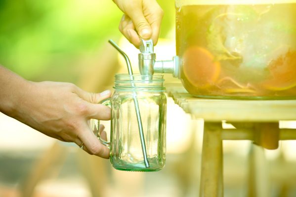woman puring lemonade in her masson jar with metal reusable straw