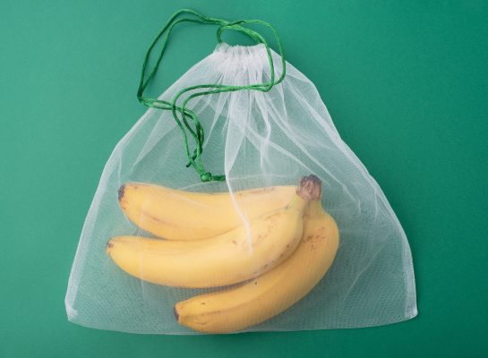 yellow-bananas-in-reusable-bag-on-green-background